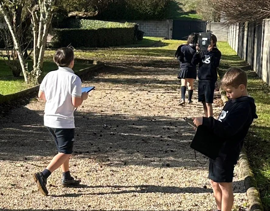 Alumnos del colegio caminando por un sendero del recinto con sus tabletas en la mano